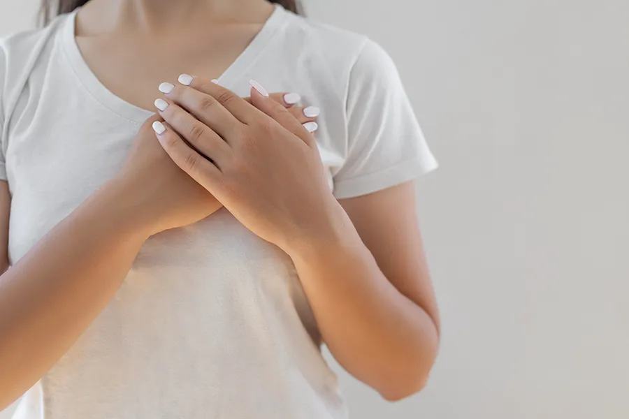 Person pressing hands to their chest, illustrating potential early warning signs of cardiac or anxiety-related symptoms